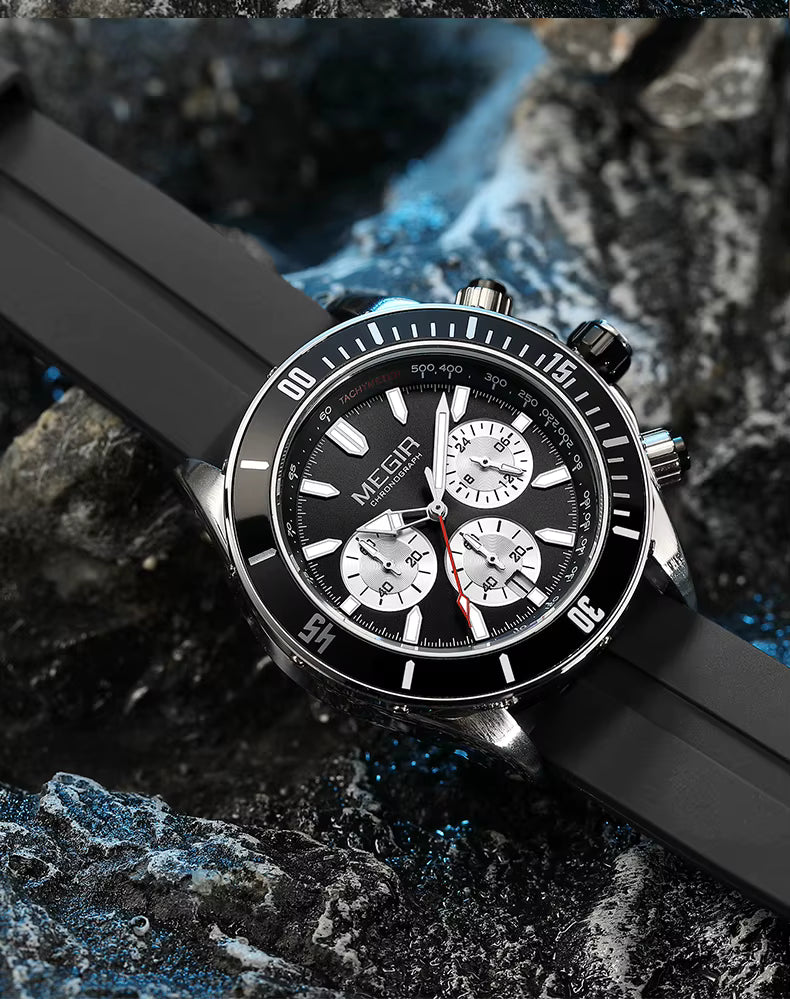 Motorsport-inspired black chronograph watch with bold dial and sporty rubber strap on rocks