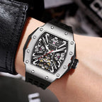 Luxury sport-inspired skeleton watch with tonneau-shaped silver case and black strap on wrist