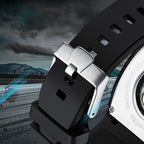 Close-up of a sport-luxury watch with black strap, stainless buckle, motorsport-inspired design, racetrack background.