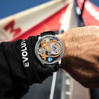 Motorsport-inspired luxury skeleton watch with intricate gold details on wrist outdoors